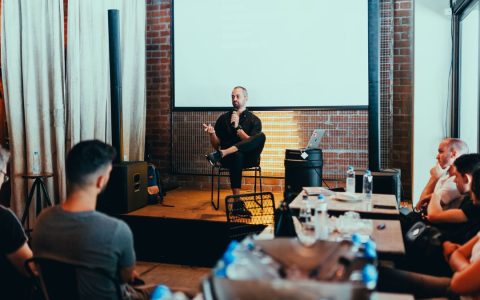 A business seminar with a speaker addressing an attentive audience in a modern conference setting.