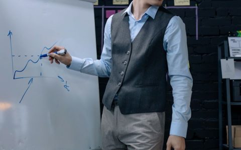 A businessman drawing a graph on a whiteboard during a presentation in an office environment.
