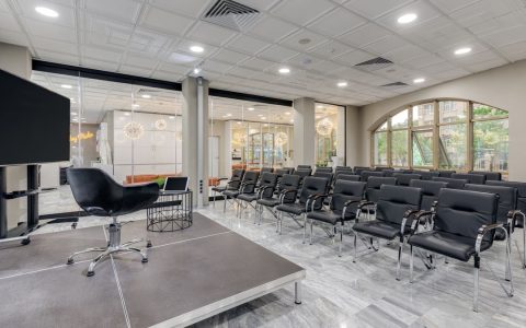 Spacious office setup with black chairs and a presentation stage.