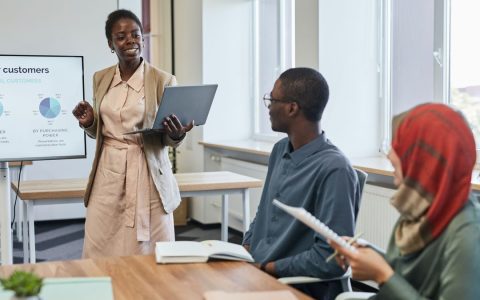 Business professionals in a meeting room focusing on a presentation with charts and data.