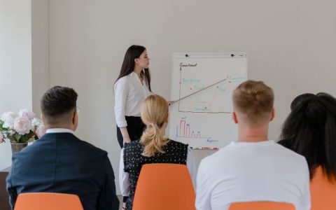 A professional conducts a presentation in an office setting to a diverse team.