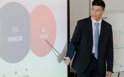 Man in suit presenting growth and promotion strategies during a meeting.